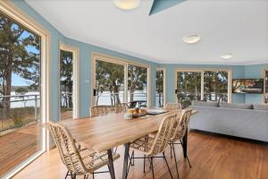 a dining room with a table and chairs and a couch at Tall Trees- Forest hideaway on Hastings Lagoon in Hastings