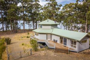 una pequeña casa blanca con techo verde en Tall Trees- Forest hideaway on Hastings Lagoon, en Hastings