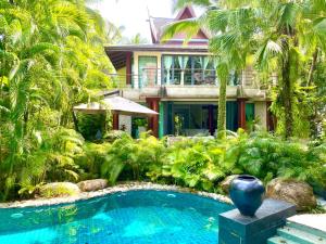 a house with a swimming pool in front of a house at Villa in the Garden, Surin Beach with private spa. in Surin Beach