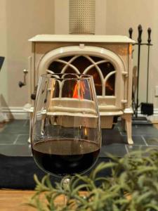 un bicchiere di vino seduto su un tavolo con camino di Cosy Country Cottage a Neerim South