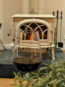 a glass of wine sitting on a table with a fireplace at Cosy Country Cottage in Neerim South