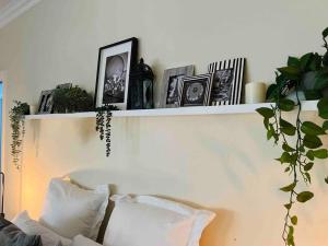 a shelf on a wall with pictures and a couch at Cosy Country Cottage in Neerim South