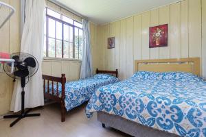 een slaapkamer met 2 bedden, een ventilator en een raam bij Caminho do Rio in Morretes