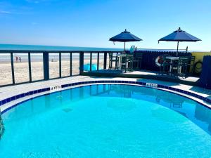 a swimming pool with the beach in the background at Beach Daze - Ocean front at Symphony Beach Club! in Ormond Beach