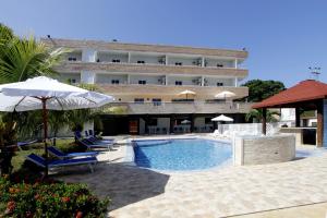 a hotel with a swimming pool with chairs and umbrellas at La Costa Playa El Agua Hotel in El Agua