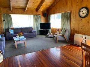 a living room with a couch and a clock on the wall at Unit 12 Kaiteri Apartments and Holiday Homes in Kaiteriteri