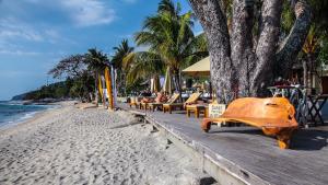 a wooden bench on a beach next to the ocean at Qunci Villas Resort in Senggigi