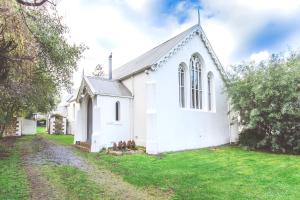 a small white church with a grass yard at Abbey on Main - Unique heritage listed property overlooking the Huon River in Franklin