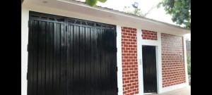 a garage with two black doors and a brick wall at Pucallpa House3 in Pucallpa