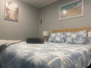 a bedroom with a bed with blue and white sheets at The Beach Hut in Tuross Heads