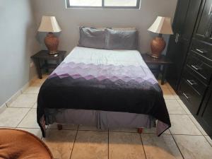 a bed in a room with two night stands and two lamps at Apartment Downtown Cananea in Cananea
