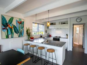 a kitchen with a island with bar stools at Mon Coeur Holiday Home in Kaiteriteri