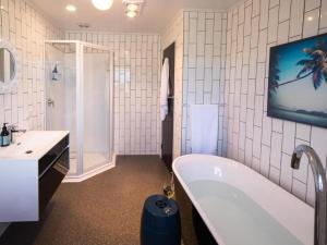 a bathroom with a tub and a tv on the wall at Mon Coeur Holiday Home in Kaiteriteri