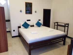 a bedroom with a large bed with blue pillows at Hotel Alaskabay Arugambay in Pottuvil