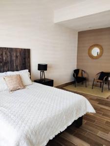 um quarto com uma grande cama branca e cadeiras em Hermosa casa para conocer León em León