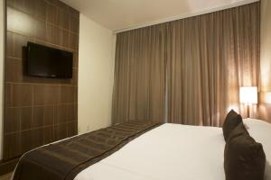 a hotel room with a bed and a flat screen tv at Casablanca Center Hotel in Petrópolis