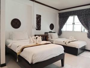um quarto com 2 camas com lençóis brancos e uma janela em Vlodge House em Chiang Mai