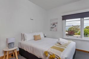 a white bedroom with a large bed and a window at Bella Vista on Beach in Hobart