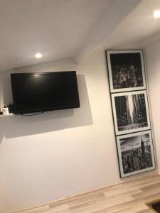 een flatscreen-tv aan een muur met twee foto's bij Studio indépendant avec terrasse-climatisation in Marseille