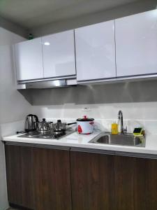a kitchen with white cabinets and a sink at Air Residences Staycation in Manila