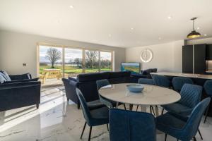 a living room with a table and blue chairs at The Stables At Mullans Bay in Kesh