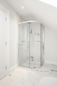 a glass shower in a white room with marble walls at The Stables At Mullans Bay in Kesh
