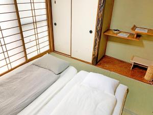 uma cama branca num quarto com uma janela em 花楓舎-Sakura & Maple Guest House-ゲストハウス em Quioto