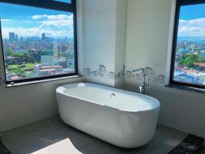 baño con bañera blanca y ventanas en Mercury Beach DaNang, en Da Nang
