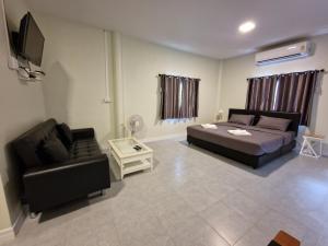 a bedroom with a bed and a couch and a tv at บังกะโลบ้านสวนเอก Bungalow Baan Suan Aek in Ban Pang Chaphlung