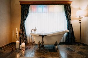 a bathroom with a tub and a window with candles at Museum Hotel in Uchisar