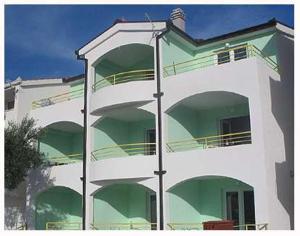 a tall white building with green balconies on it at apartmani Natali in Podaca