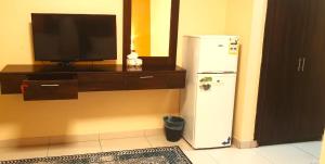 a kitchen with a television and a white refrigerator at فندق 7c in Al Hofuf