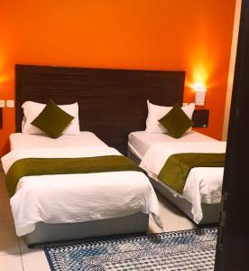two beds in a hotel room with orange walls at فندق 7c in Al Hofuf