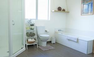 a bathroom with a tub and a toilet and a shower at Vines on Bannockburn in Cromwell