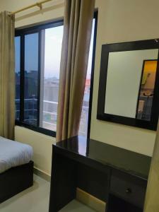 Kavre Guest House في لومبيني: غرفة نوم مع مرآة ومكتب ونافذة