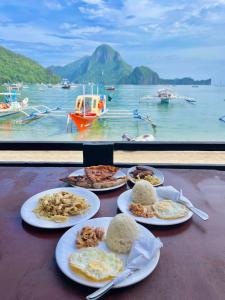 4 platos de comida en una mesa con vistas al agua en Joyful Guest House, en El Nido