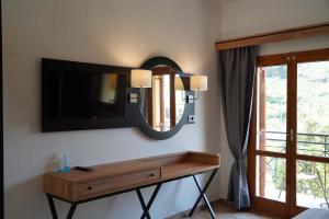Zimmer mit einem TV und einem Tisch mit einem Spiegel in der Unterkunft Angelika Elegant Hotel in Parga