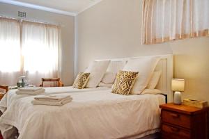 a bedroom with a large bed with white sheets and pillows at Chesham House in Hermanus