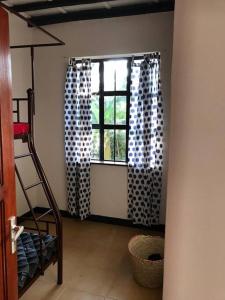 姆托瓦姆布的住宿－The Hondo Hondo House, Mto wa Mbu，带窗帘和梯子的窗户的房间