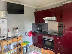 a kitchen with red cabinets and a stove at Stella le Touquet Berck T2 in Stella-Plage