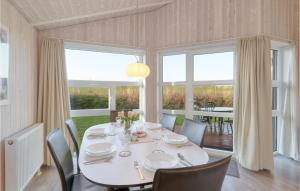 une salle à manger avec une table, des chaises et des fenêtres dans l'établissement Friedrichskoog-Strandpark 16, à Friedrichskoog