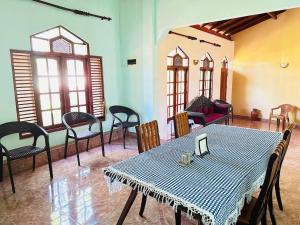 comedor con mesa, sillas y ventanas en Lakbima Holiday Lodge, en Devinuwara