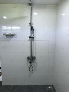uma cabina de duche numa casa de banho em azulejos brancos em aji fruit farm em Embilipitiya