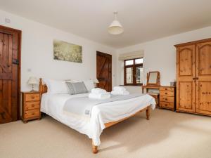 a bedroom with a large bed and wooden cabinets at Castle Dore Barn in Par