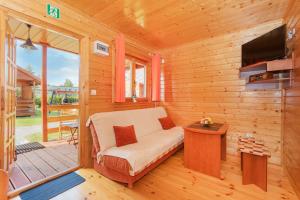 Habitación con sofá y TV en una cabina. en Domki Letniskowe Patryk - 300m od plaży en Darlowko