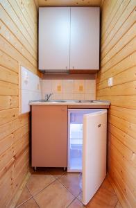 a small kitchen with a refrigerator and cabinets at Domki Letniskowe Patryk - 300m od plaży in Darłówko