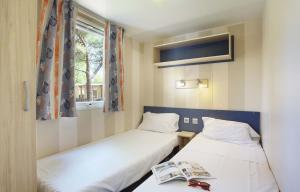 2 camas en una habitación pequeña con ventana en Mobil home 6 ou 8 pers Au camping Le Grau-du-Roi Domaine l'Elysée, en Le Grau-du-Roi