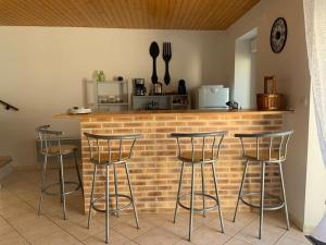 um bar com quatro bancos em frente a um balcão de tijolos em Maison bord du Thouet/ parking/ terrasse / fibre em Taizé