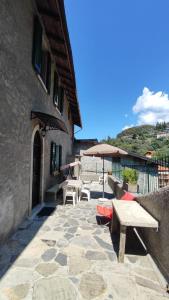 eine Terrasse mit Bänken und Tischen und einem Sonnenschirm in der Unterkunft Casa Angela in Perledo