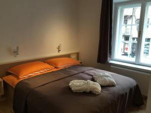 ein Bett mit orangefarbenen Kissen und zwei Handtüchern darauf in der Unterkunft Apartments City&style in Zagreb